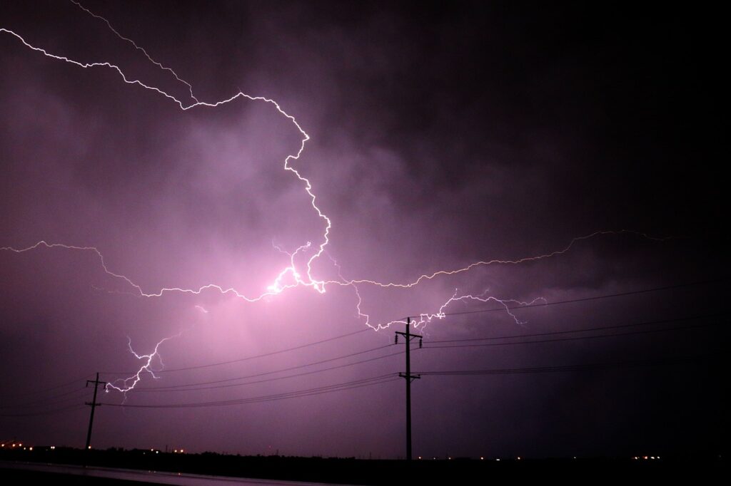 A lightning bolt or thunderstorm reaching electrical poles from sky clouds. 